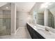 Bathroom with double sinks, tile floors, gray walls, a large mirror, and a walk-in shower with pebble flooring at 4782 Night Star Trl, Odessa, FL 33556