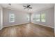 Bright bedroom featuring tray ceiling, ceiling fan, hardwood floors and multiple windows providing ample natural light at 4782 Night Star Trl, Odessa, FL 33556