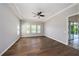 Spacious bedroom with wood flooring, tray ceiling, fan, three windows, and doorway to the outdoors at 4782 Night Star Trl, Odessa, FL 33556