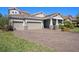 Charming home with a three-car garage, brick driveway, lush landscaping, and a covered front porch at 4782 Night Star Trl, Odessa, FL 33556