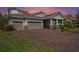 Charming home featuring a three-car garage, tile roof, and well-manicured landscaping, enhanced by a brick driveway at 4782 Night Star Trl, Odessa, FL 33556