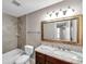 Bathroom featuring a tub with shower, granite countertop with dark wood cabinetry and a large mirror at 5159 Sterling Manor Dr, Tampa, FL 33647