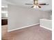 Carpeted loft area with neutral colored walls, ceiling fan, and a glimpse into the kitchen area at 5159 Sterling Manor Dr, Tampa, FL 33647