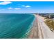 Expansive aerial view of the beach with blue water, white sand, and city skyline on a sunny day at 5625 Escondida S Blvd, St Petersburg, FL 33715
