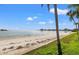 Stunning beach view featuring sugar sand and turquoise water against a clear blue sky with a palm tree foreground at 5625 Escondida S Blvd, St Petersburg, FL 33715