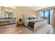 Bright, staged bedroom with updated flooring, ensuite bathroom, and sliders to a balcony at 5625 Escondida S Blvd, St Petersburg, FL 33715