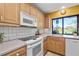This kitchen features stainless steel appliances, wood cabinets, tile backsplash, and a window view to the golf course at 5625 Escondida S Blvd, St Petersburg, FL 33715