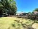 Spacious backyard featuring a wooden fence, mature trees, and a covered patio area at 6701 Medlar Dr, New Port Richey, FL 34653