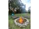 Outdoor fire pit with stone surround and benches, creating a cozy gathering space in a leafy backyard at 6701 Medlar Dr, New Port Richey, FL 34653
