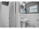 Cozy white bathroom features a pedestal sink, mirrored cabinet, and window with a view at 724 38Th Ne Ave, St Petersburg, FL 33704