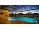 Screened pool area with sun loungers, pool lights, and views of the fenced backyard with playground at 8141 Carlton Ridge Dr, Land O Lakes, FL 34638