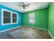A bedroom with blue and green walls features hardwood floors, ample natural light, and a ceiling fan at 8719 N Ola Ave, Tampa, FL 33604
