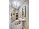 Elegant powder room featuring a pedestal sink, decorative mirror, and stylish light fixture at 9314 Heritage Oak Ct, Tampa, FL 33647