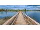 Picturesque view of a wooden dock extending over a serene lake with lush green surroundings and a cloudy sky at 9314 Heritage Oak Ct, Tampa, FL 33647