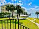 Beautiful exterior view of building, palm trees, manicured lawn, and waterfront pier create the perfect landscape for a luxury lifestyle at 100 Bluff View Dr # 117C, Belleair Bluffs, FL 33770