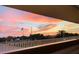 Balcony view of sunset, bridge, US flag, palm trees, and highway provides a diverse scenic perspective of the property's location at 100 Bluff View Dr # 117C, Belleair Bluffs, FL 33770