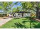 Charming single-story home with white exterior, dark roof, and mature trees at 1104 S Lois Ave, Tampa, FL 33629