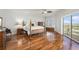 Bright main bedroom featuring hardwood floors, ceiling fan, and sliding glass doors to balcony at 11525 Gulf Blvd # 401, Treasure Island, FL 33706