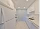 Galley kitchen featuring all-white cabinets, appliances and contrasting blue panel wall at 124 Gloucester Blvd # 355J, Sun City Center, FL 33573