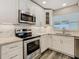 Kitchen featuring stainless steel appliances, white cabinets, and updated backsplash at 1247 Holiday Dr, Tarpon Springs, FL 34689
