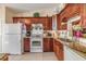 Well-appointed kitchen featuring granite countertops, white appliances, and wood cabinets at 1333 Shady Pine Way # B, Tarpon Springs, FL 34688