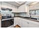 Well-lit kitchen boasts sleek black countertops, hexagon backsplash and white cabinets at 14713 Pine Glen Cir, Lutz, FL 33559