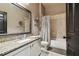 Bathroom with a granite vanity, decorative mirror, and tiled shower/tub combo with neutral tile and curtain at 14885 Caravan Ave, Odessa, FL 33556