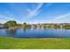 Community lake view surrounded by lush green grass and a variety of home exteriors at 14885 Caravan Ave, Odessa, FL 33556