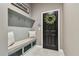 Mudroom features a built-in bench with storage and coat hooks near a black door with a decorative wreath at 14885 Caravan Ave, Odessa, FL 33556