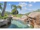 Waterfall feature spilling into the lagoon-style pool with tropical landscaping create a peaceful backyard at 19530 Barrie Acres Trl, Odessa, FL 33556