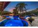 Night view of a pool with a hot tub, featuring landscape lighting and tropical palm trees at 19530 Barrie Acres Trl, Odessa, FL 33556
