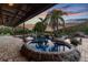 Pool area showcasing a hot tub, palm trees, and a rock-lined design against a vibrant sunset sky at 19530 Barrie Acres Trl, Odessa, FL 33556