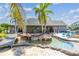 An island pool with a bridge, palm trees, stone accents, and blue lounge chairs adds to the resort atmosphere at 19530 Barrie Acres Trl, Odessa, FL 33556