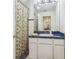 Stylish bathroom with blue countertops, white cabinets and eye-catching shower curtain at 19530 Barrie Acres Trl, Odessa, FL 33556
