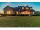 Well-maintained home exterior with a charming front porch and a lush green lawn at twilight at 19530 Barrie Acres Trl, Odessa, FL 33556