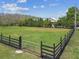 Property with black fenced yard and a home surrounded by large trees at 19530 Barrie Acres Trl, Odessa, FL 33556