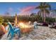 Outdoor fire pit with blue Adirondack chairs and palm trees for a relaxing backyard setting at 19530 Barrie Acres Trl, Odessa, FL 33556