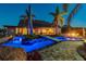 Stunning backyard pool area with tropical landscaping, an illuminated bridge, and fire pit at 19530 Barrie Acres Trl, Odessa, FL 33556
