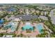 An aerial view of the community pool, waterpark, clubhouse, and surrounding residences in a lush green landscape at 2468 Coco Palm Cir, Wesley Chapel, FL 33543