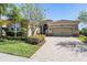Charming single-story home featuring a well-manicured lawn and an attached two-car garage with a brick-paved driveway at 2468 Coco Palm Cir, Wesley Chapel, FL 33543
