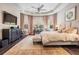 Well-lit primary bedroom with tray ceiling, TV, and a sitting area at 2468 Coco Palm Cir, Wesley Chapel, FL 33543