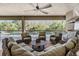 Cozy outdoor living space features comfortable seating, a ceiling fan, a built-in grill, and views of the pool and landscaping at 2468 Coco Palm Cir, Wesley Chapel, FL 33543