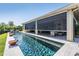 The modern pool is equipped with an automated screen system and overlooks the lush backyard landscaping, perfect for outdoor enjoyment at 2468 Coco Palm Cir, Wesley Chapel, FL 33543