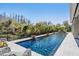 A pristine pool features deck jets, a sleek, modern design, and ample poolside seating with a beautiful wooded view at 2468 Coco Palm Cir, Wesley Chapel, FL 33543