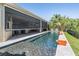 A sleek pool is equipped with a retractable screen offering an indoor-outdoor living experience with landscaped backyard views at 2468 Coco Palm Cir, Wesley Chapel, FL 33543