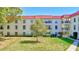 Condo with red tile roof and lush green lawn and mature tree in front at 2700 Bayshore Blvd # 4204, Dunedin, FL 34698