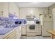 Bright kitchen with white cabinetry, stainless steel appliances, and mosaic tile backsplash at 2700 Bayshore Blvd # 4204, Dunedin, FL 34698
