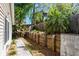 A private fenced backyard features a retaining wall and lush landscaping with shade trees and greenery at 275 S Highland Ave, Tarpon Springs, FL 34689