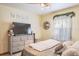 Bedroom featuring a large dresser with a television and cozy, neutral decor with a decorative window at 275 S Highland Ave, Tarpon Springs, FL 34689