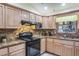 Close-up of kitchen with granite countertops, stone backsplash, black appliances, and natural wood cabinets at 275 S Highland Ave, Tarpon Springs, FL 34689